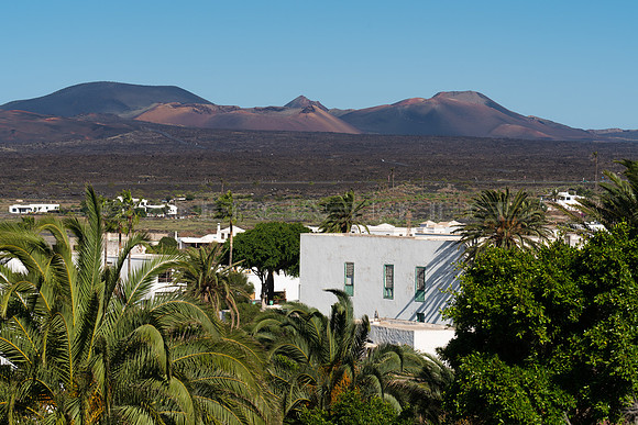 Casas y palmeras de Yaiza ante los volcanes del Parque Nacional