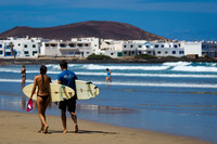 Una pareja de surfistas ante el pueblo costero de La Caleta de Famara, Teguise.